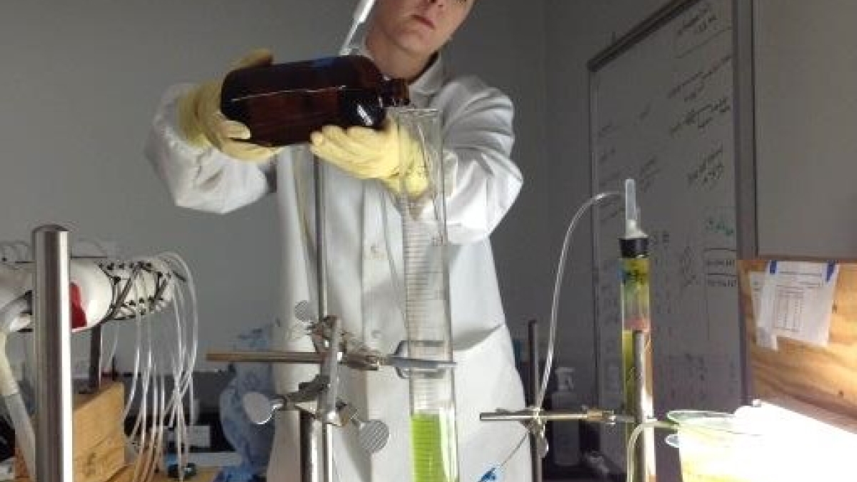 student pouring growth media into algae-filled column