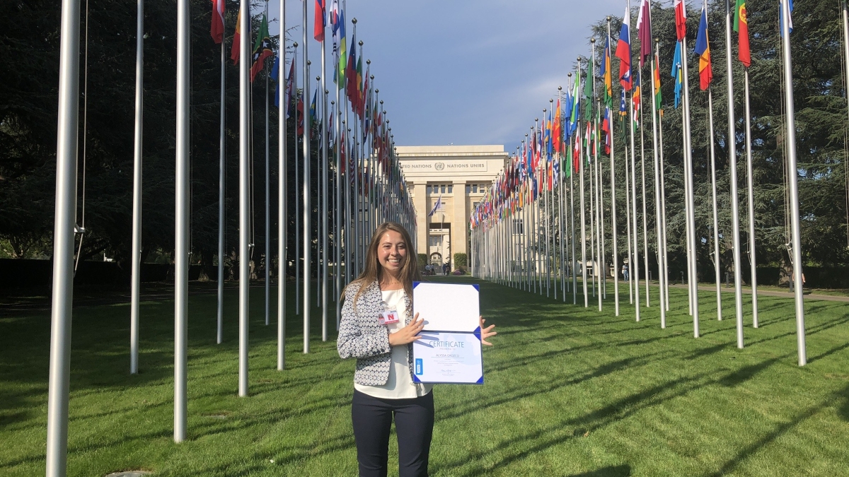 woman standing in front of United Nations flags with certificate