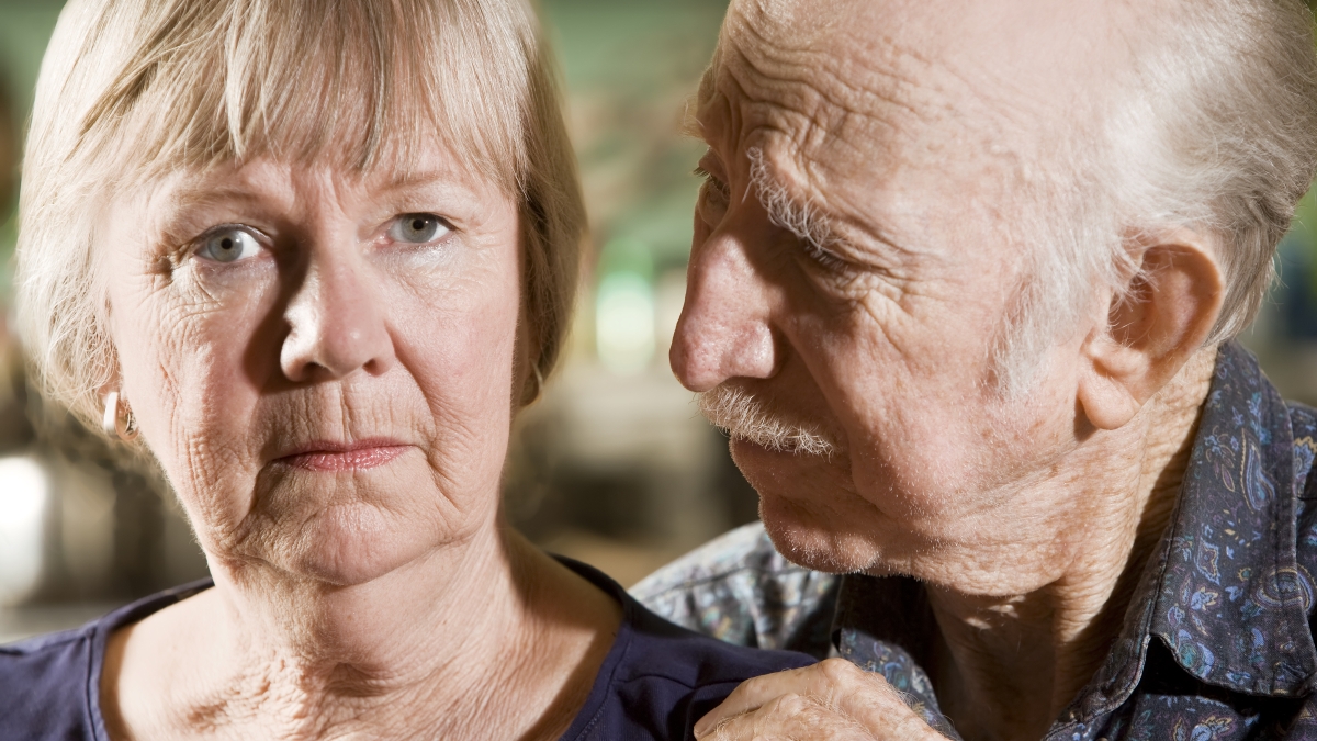 older man looks at wife, who is staring out