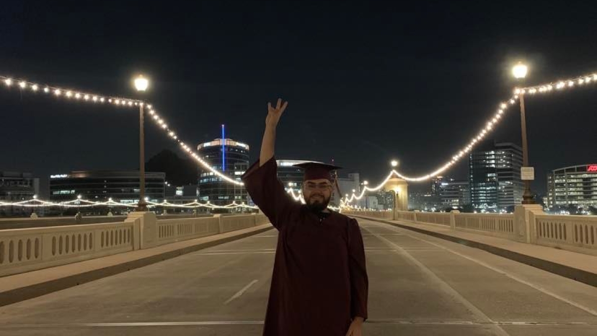 ASU grad Angel Morales giving a forks up on the Mill Avenue bridge