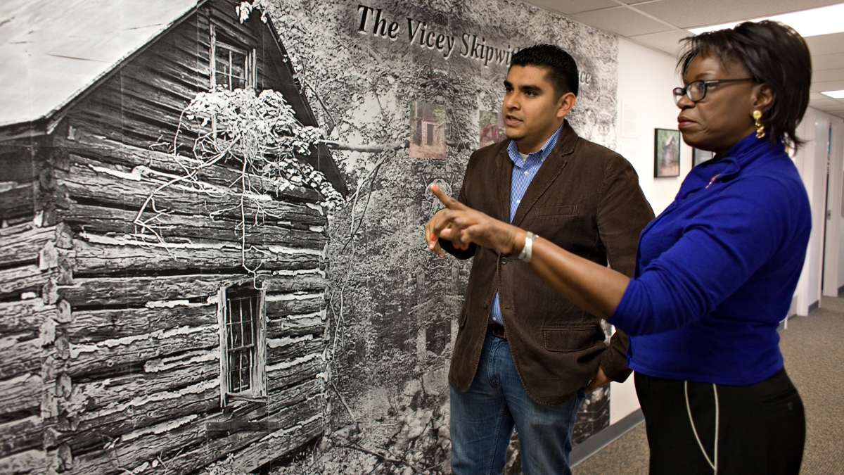 Professor Angelita Reyes converses with Jose Flores in front of mural 