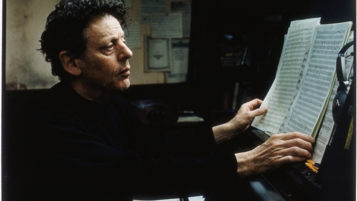 Philip Glass reading sheet music at a piano