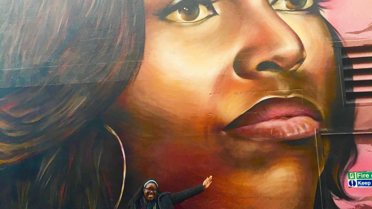 Woman standing in front of a mural of Michelle Obama.