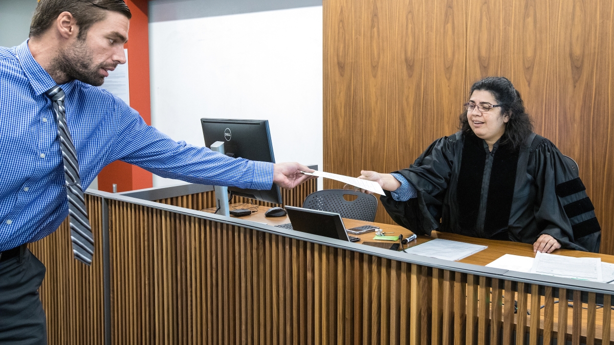 man passing woman dressed as a judge a piece of paper