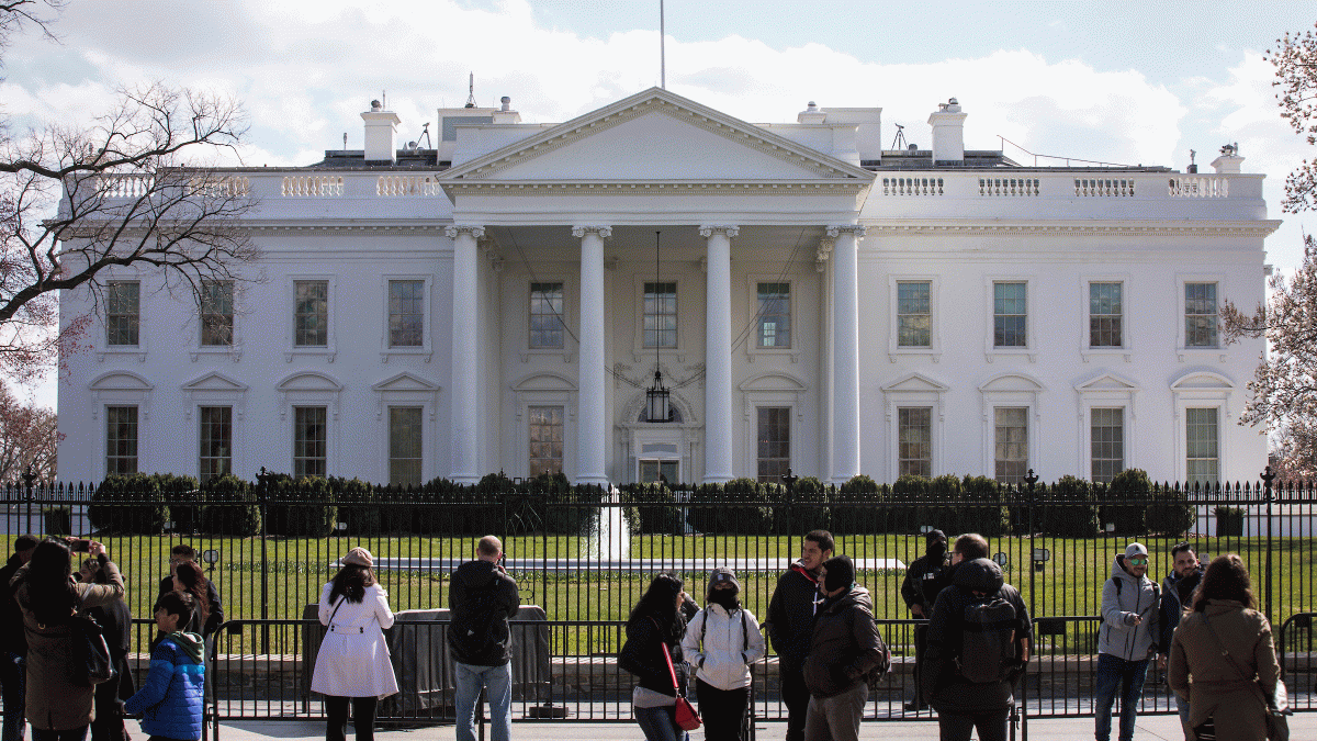 People take photos in front of the White House