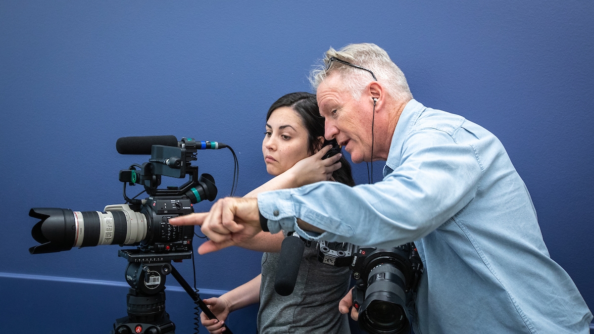 Woman and man looking through video camera