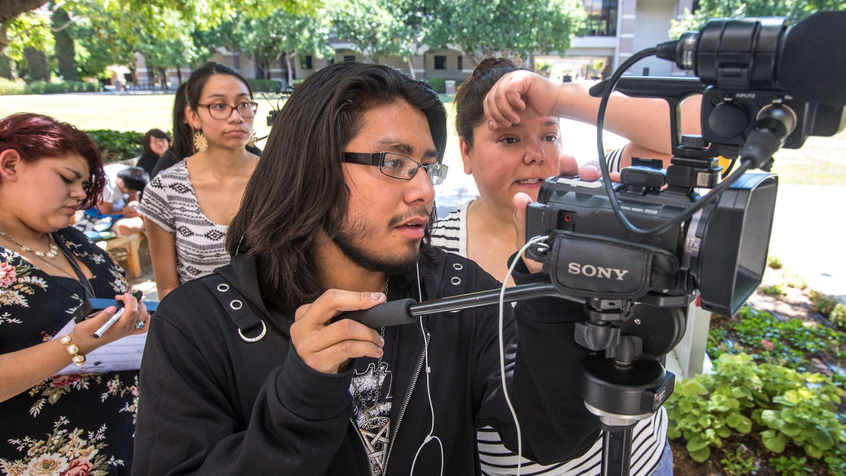 people standing behind a film camera