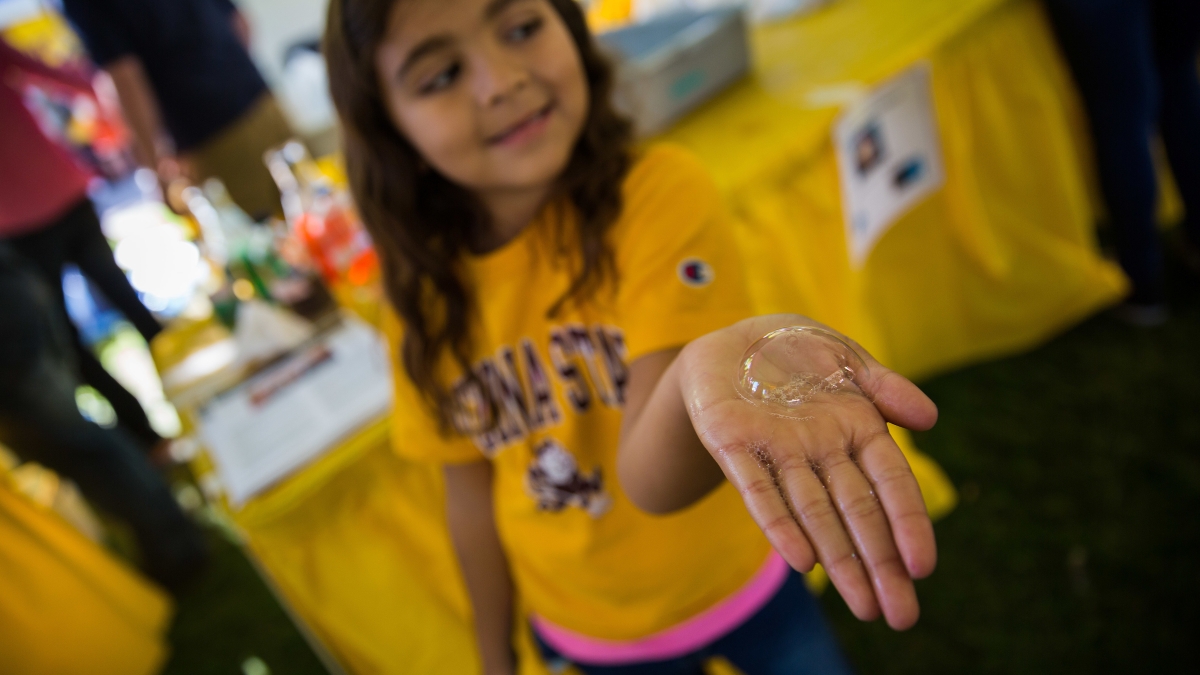 A girl holds a bubble on her hand from the 2015 Homecoming Block Party