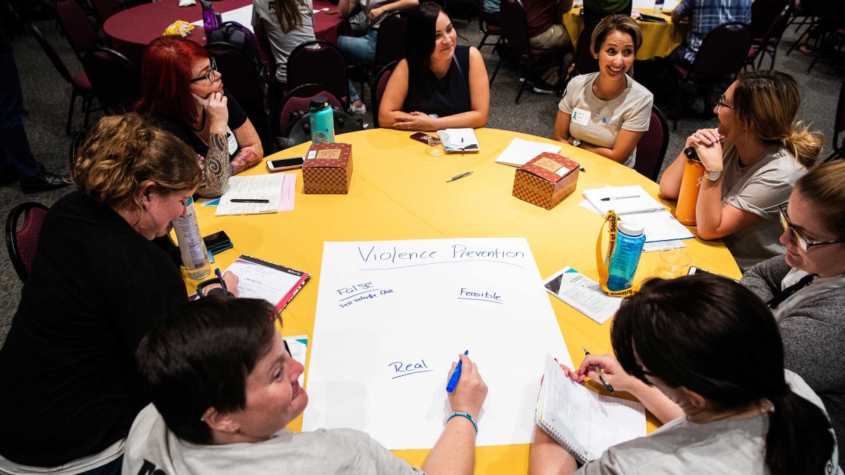 Participants at a conference on preventing domestic violence write ideas on a poster