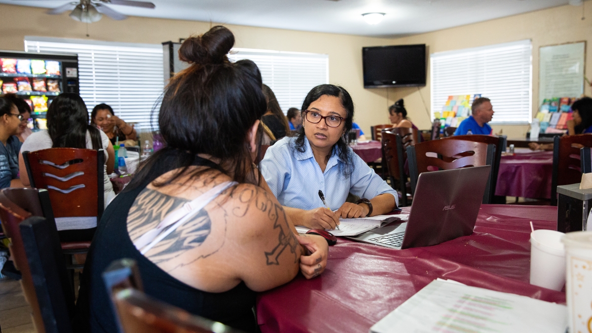 woman speaking to another woman at a table