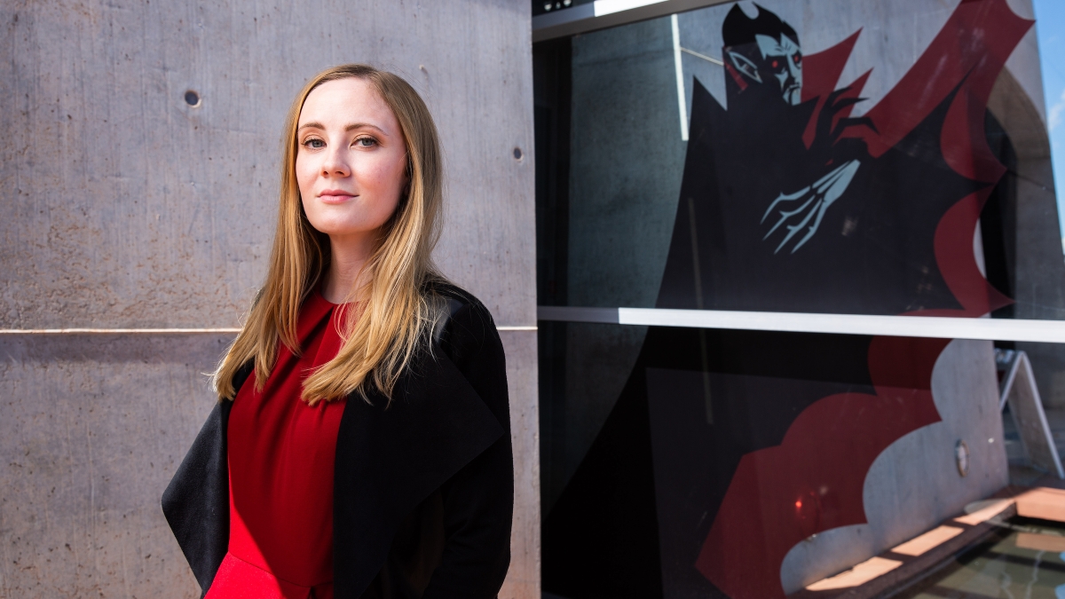 woman standing next to a painting of dracula