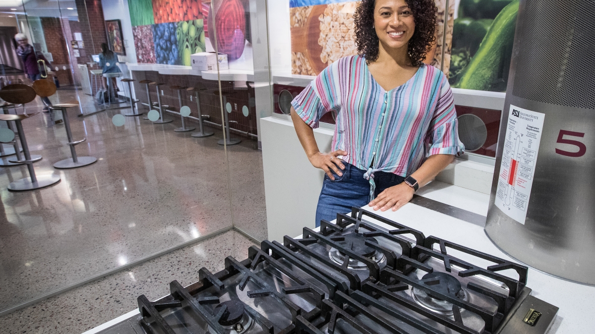 woman standing by a stove top, smiling
