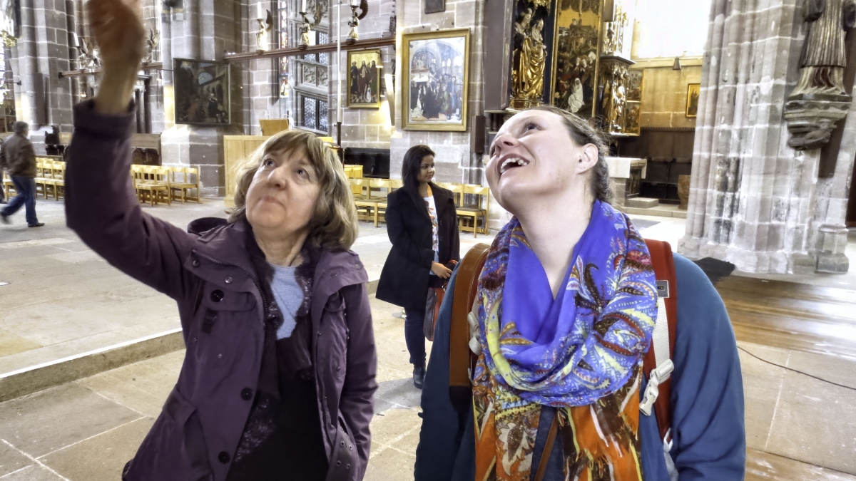 woman pointing up while another woman looks up in an old church