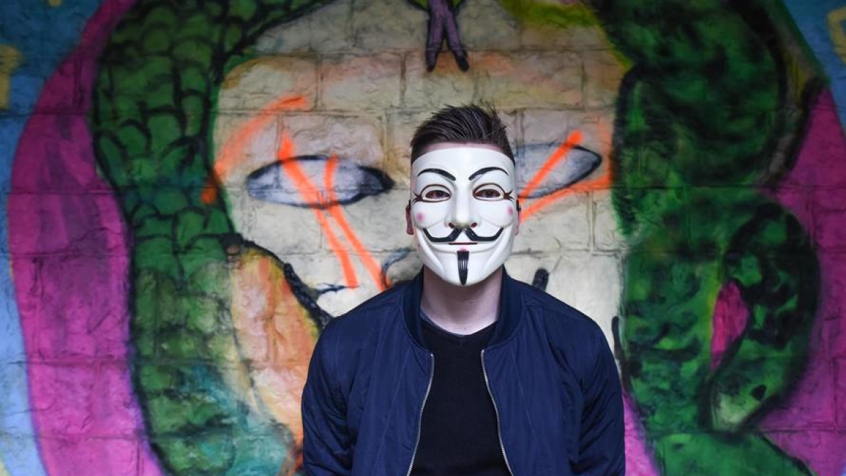 man in mask in front of graffiti wall