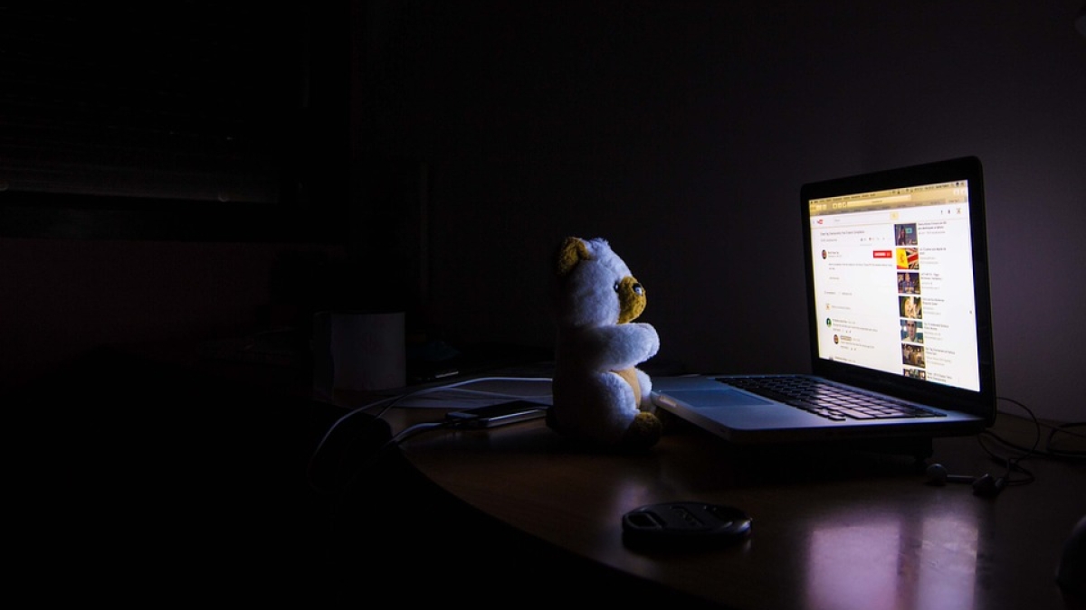 stuffed bear looking at bright computer screen in dark room
