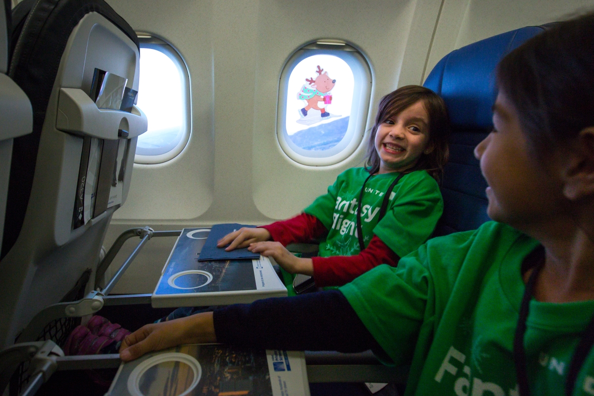 Children smile on an airplane.