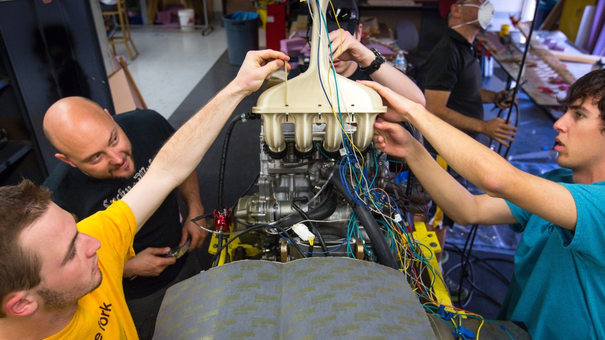 Students work on a throttle in a Formula-style race car.