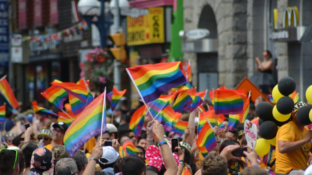 people marching down a street waving rainbow flags