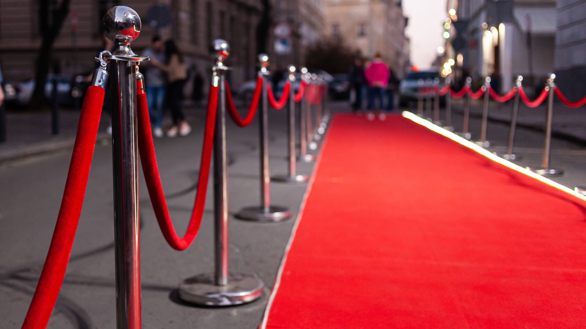 Stock photo of red carpet rolled out with ropes and poles alongside it