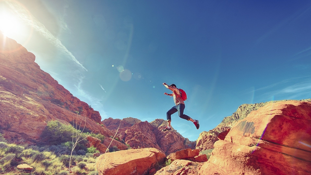 hiker jumping from rock to rock