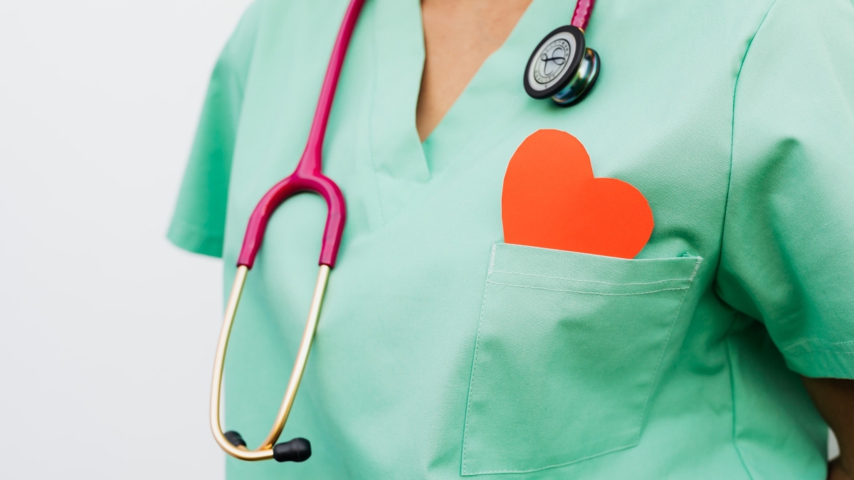 person in scrubs with stethoscope around neck and paper heart in pocket