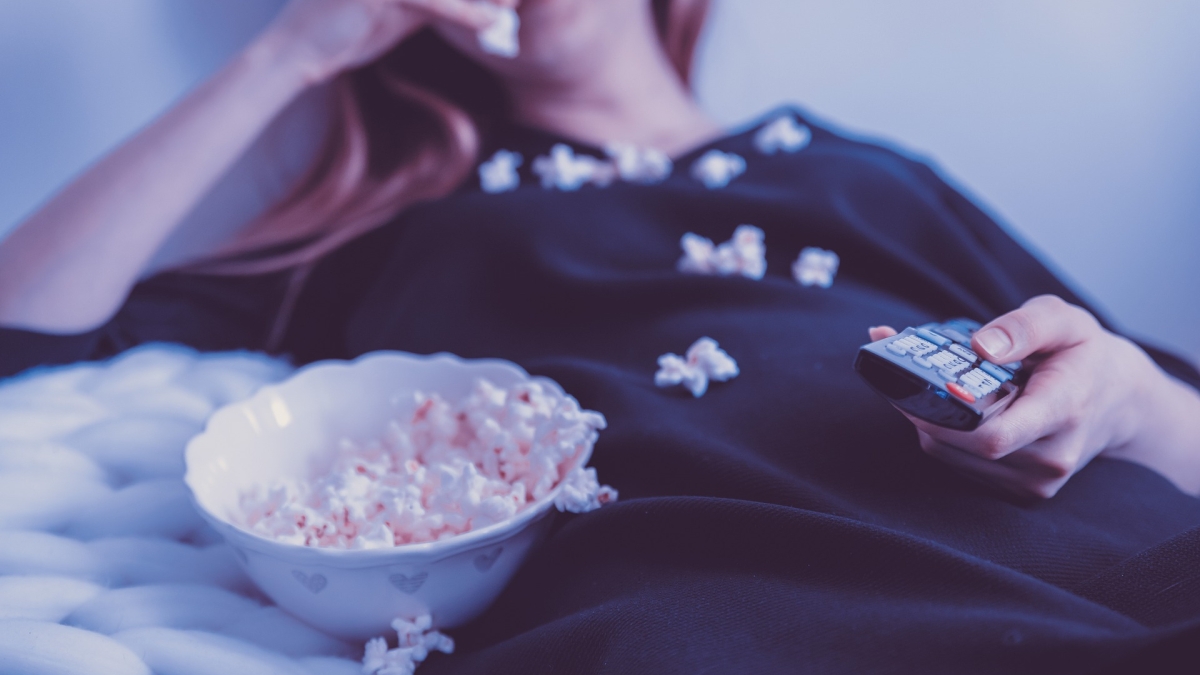 person eating popcorn while holding a remote