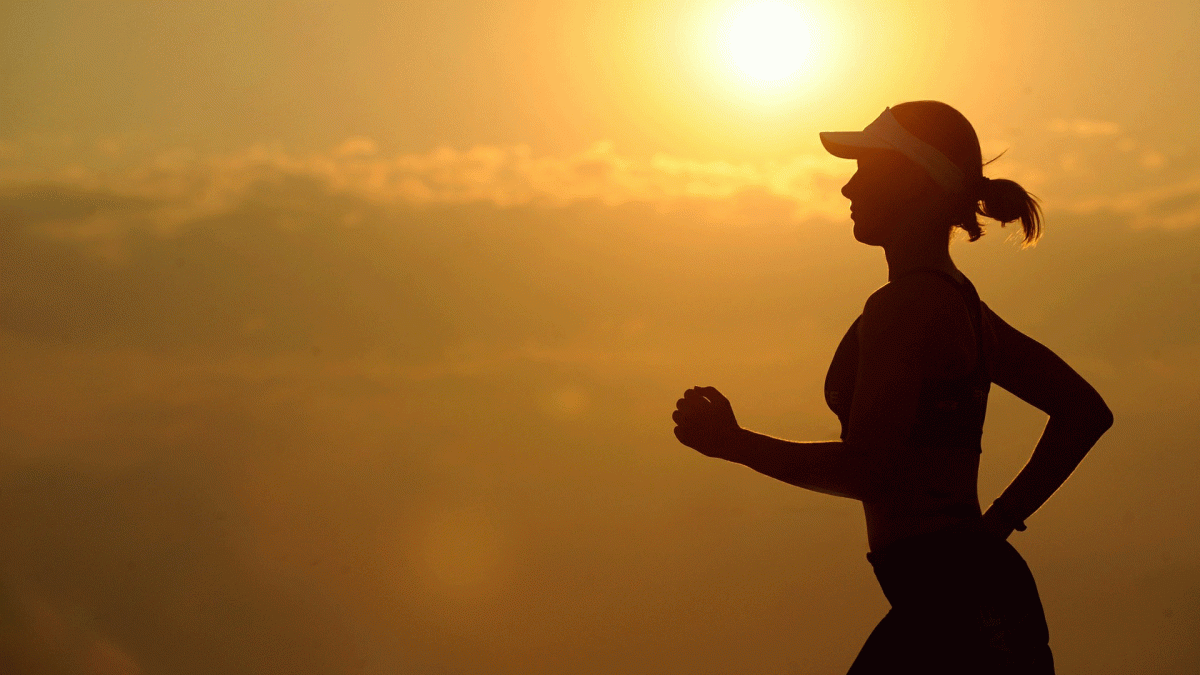 A runner is silhouetted against the sun