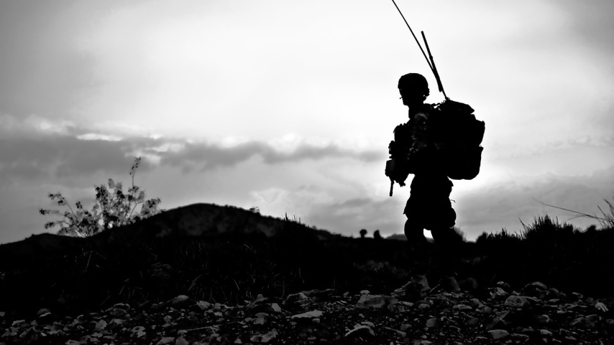 black and white photo of landscape with a soldier silhouetted in the foreground