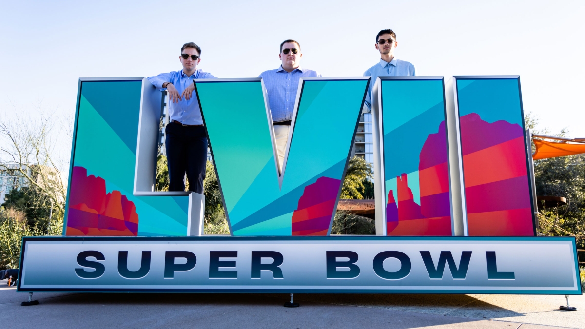 Trio of ASU students standing behind Super Bowl sign in Phoenix.