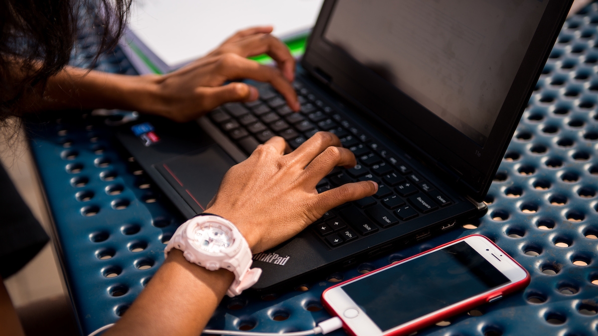 A high schooler's hands working on a laptop