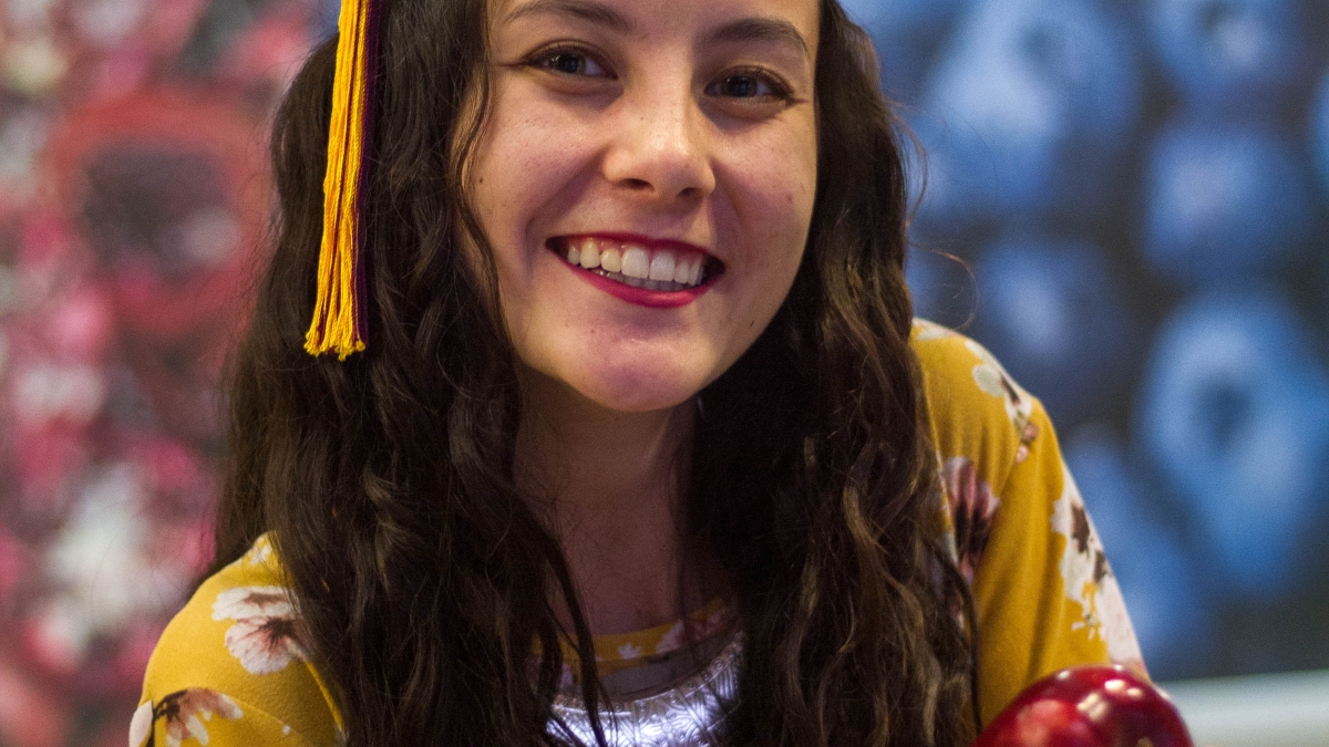 Dahlia Stott in her graduation cap holding apples