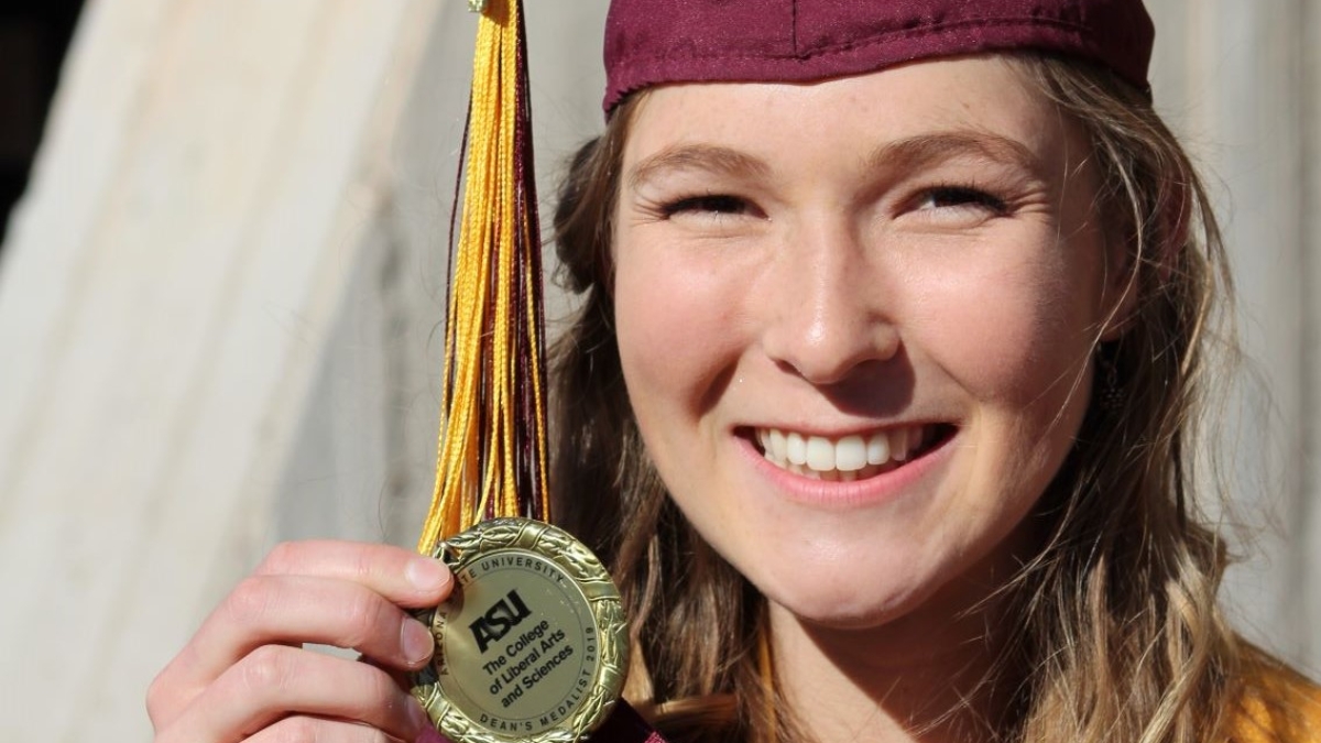 Lindsay Lohr in her ASU cap and gown holding her Dean's medal