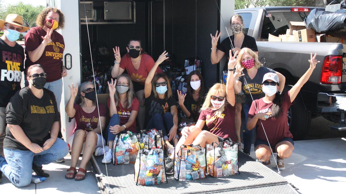 ASU Moms in masks giving forks up in front of a truck with care packages