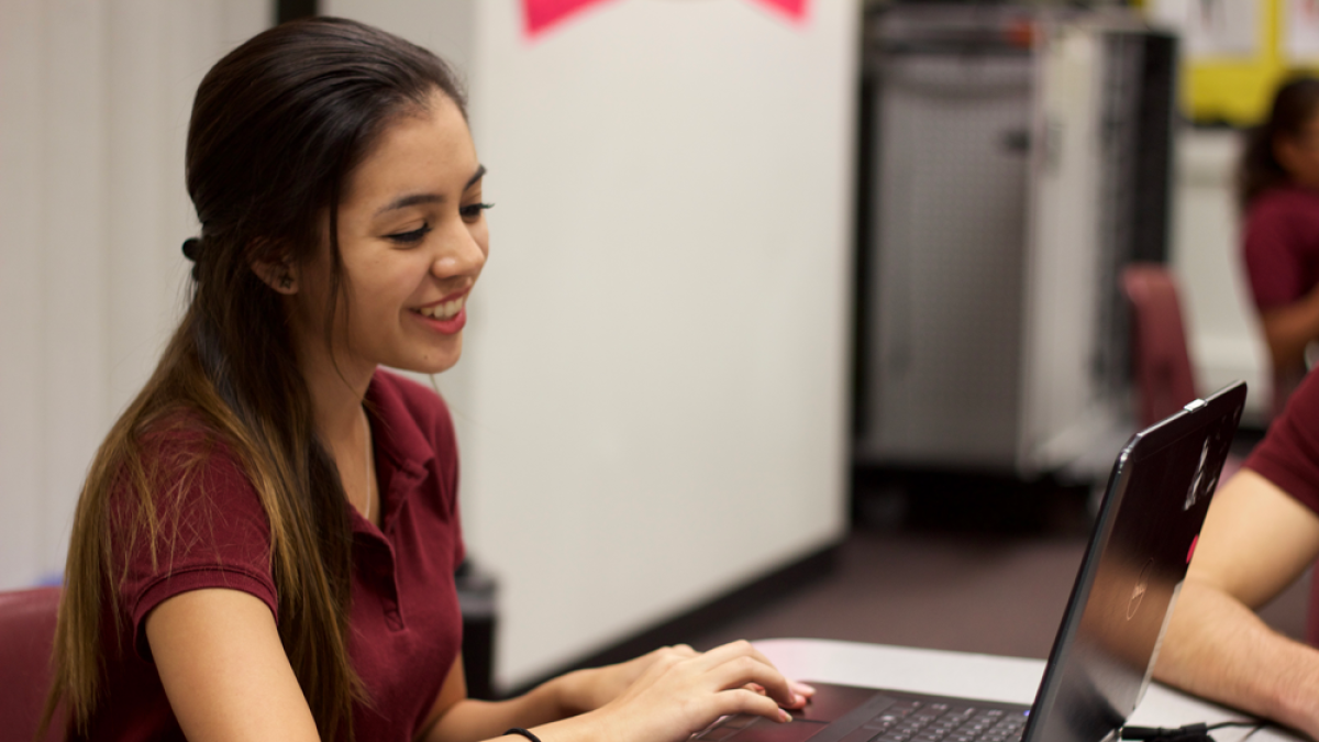 A middle school female student grins at her computer at ASU Prep Phoenix Middle School.
