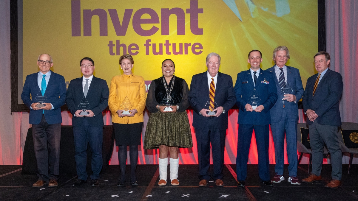 Group photo of people standing on stage holding awards.