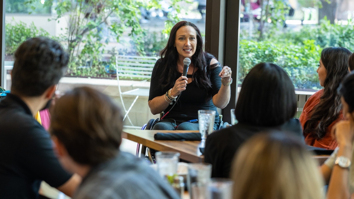 Olympic gold medalist Amy Van Dyken-Rouen seated in a wheelchair and holding a microphone while speaking to ASU College of Health Solutions students.