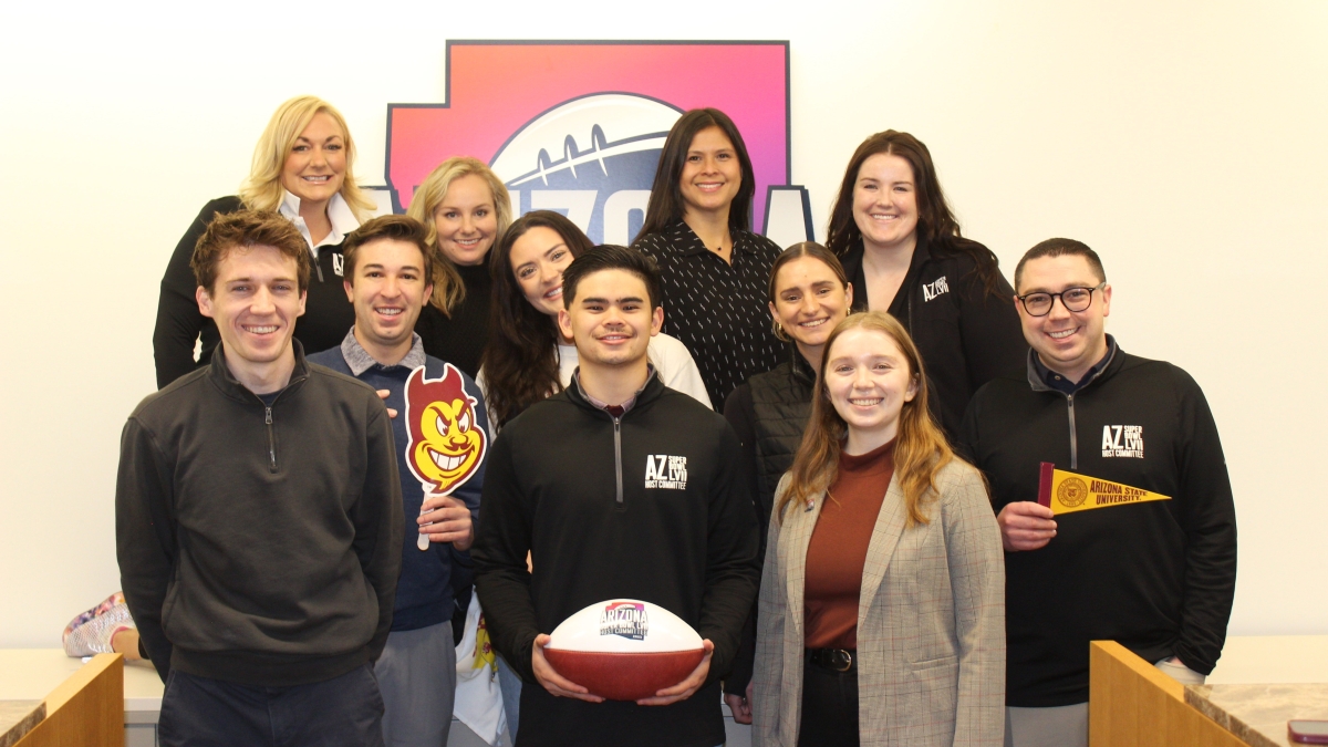 Group of ASU students and alums who make up the Super Bowl Host Committee posing with a cardboard cutout of Sparky the Sun Devil and a football.