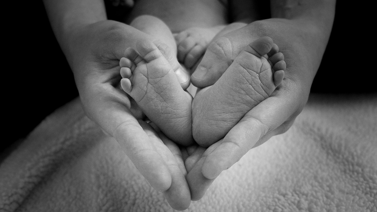 Hands holding baby feet in a heart shape