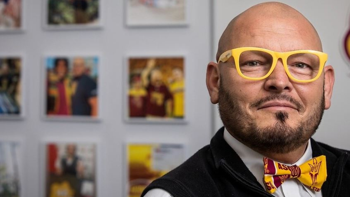 Shawn Banzhaf, assistant director of student success in the Pat Tillman Veterans Center at Arizona State University, poses for a photo in ASU gold glasses and ASU themed bowtie.