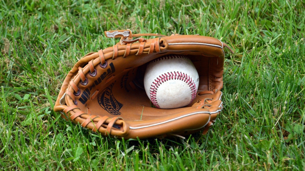 baseball mitt lying on the grass with a ball inside of it 