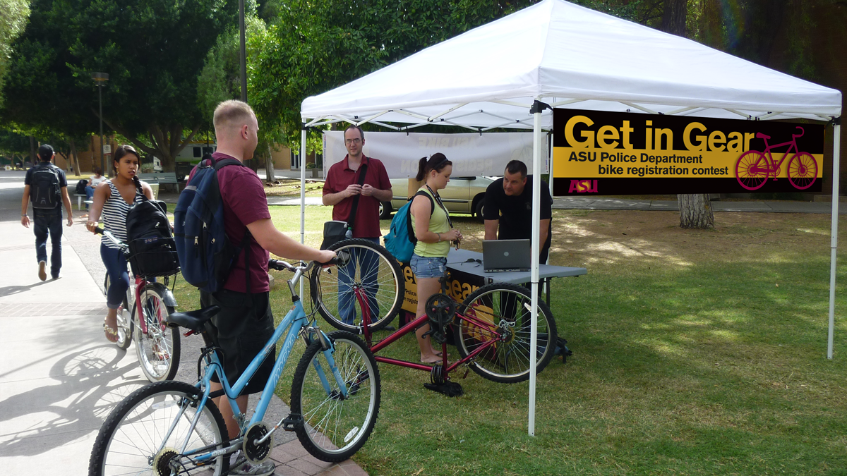 Students and their bicycles surround an outside tent.