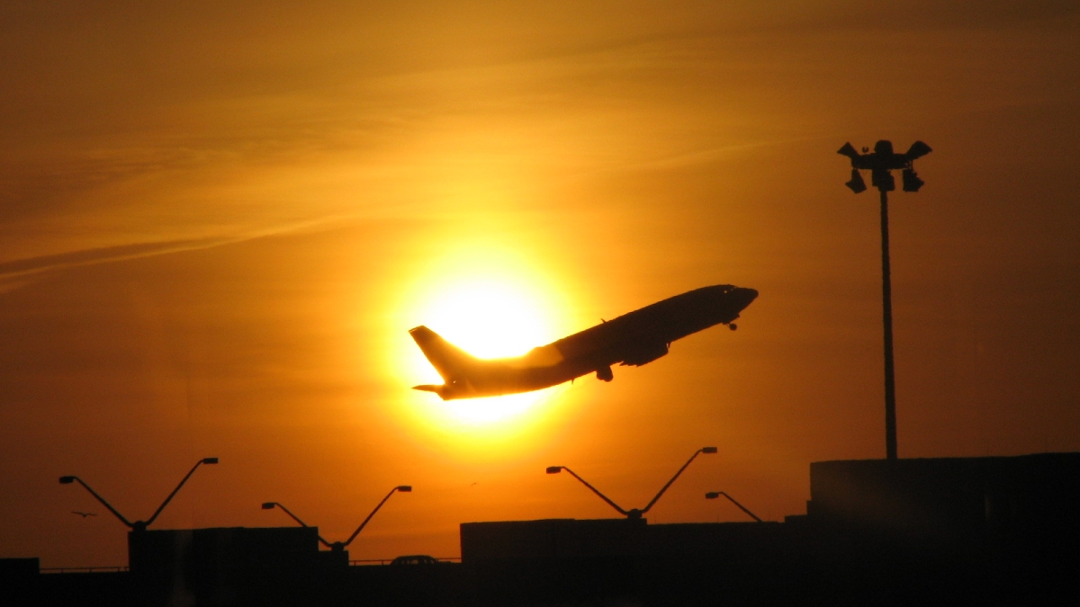 A plane takes off against the sunset