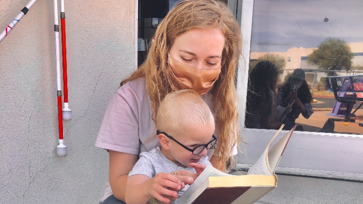 woman holding young blind child with book