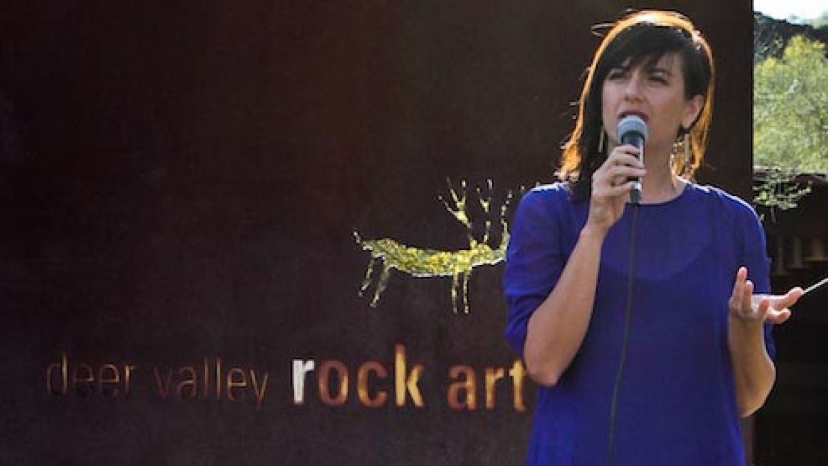 Casandra Hernandez speaking into microphone at Deer Valley Rock Art Center