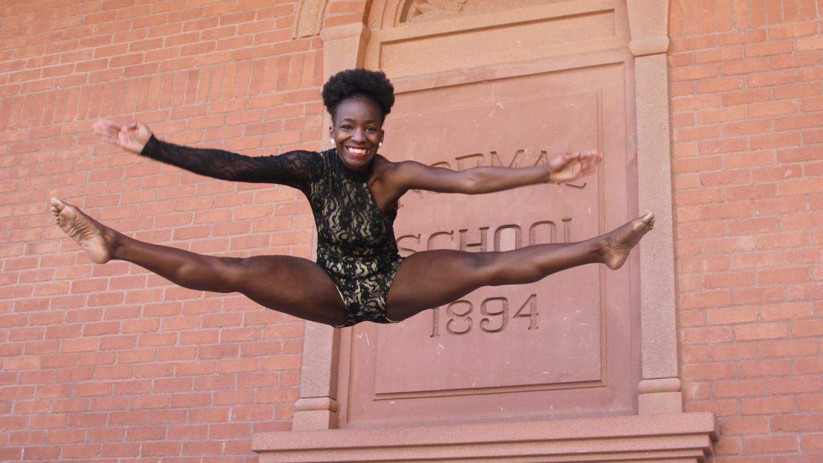 woman in dance pose in front of Old Main building