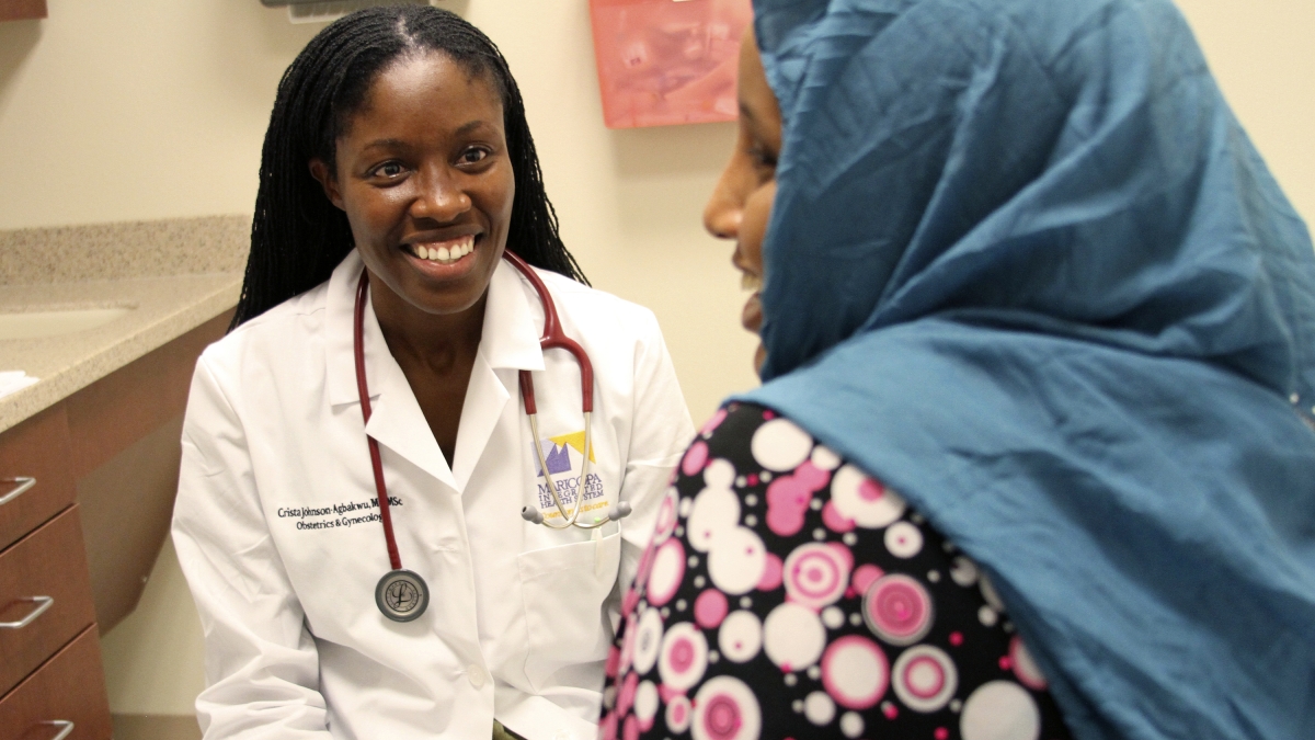 Dr. Crista Johnson-Agbakwu talks with refugee patient in a clinic room