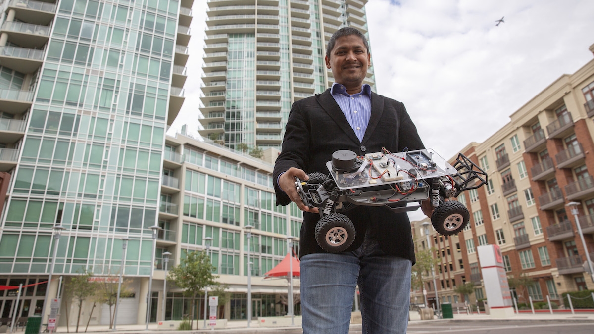 ASU Asscoiate Professor Aviral Shrivastava holds a miniature autonomous vehicle