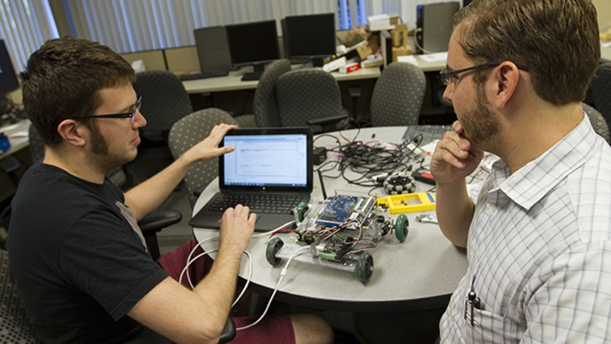 two ASU engineering students talking with a robot on a table