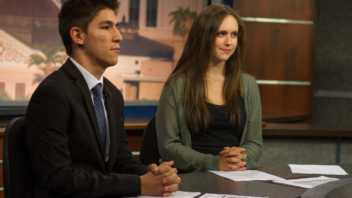 journalism students sitting at a news desk