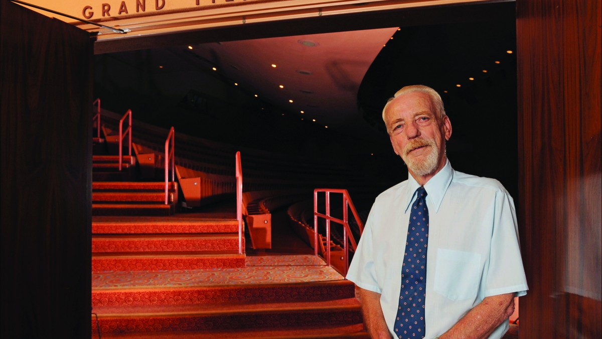 A man stands in front of the entrance to a theater.